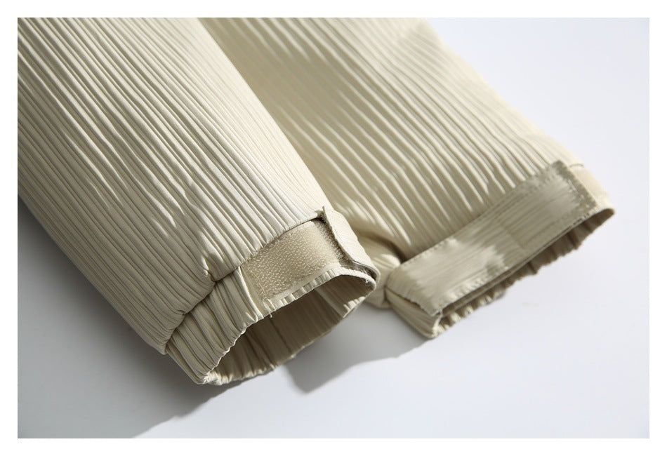 Close-up of an ivory pleated sleeve cuff with an adjustable hook-and-loop tab.