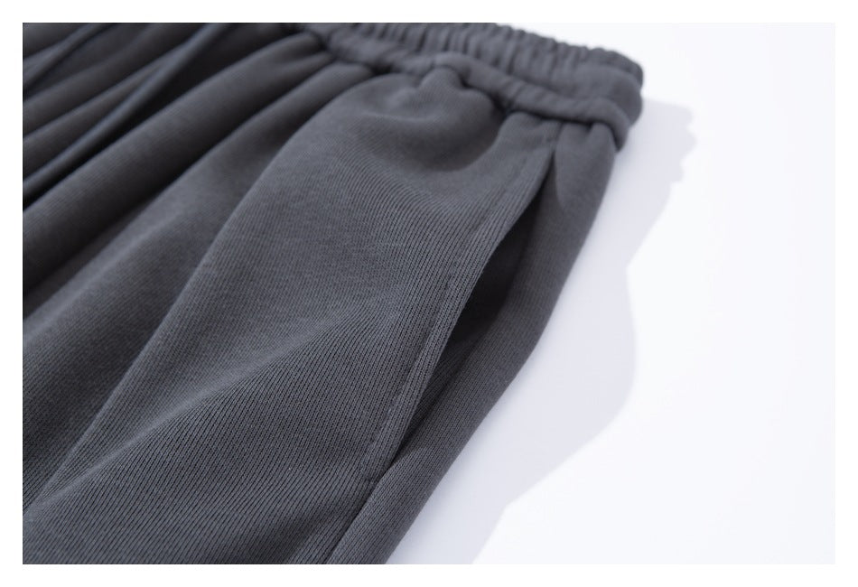 Close-up of the charcoal pants leg and side seam beneath the gathered waistband.