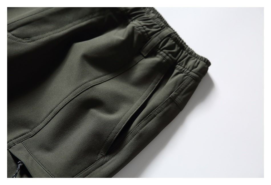 Close-up of dark olive pants showing the elastic waistband and a long side pocket.