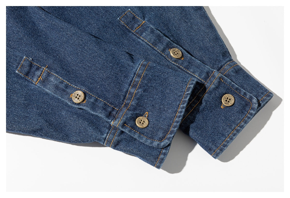 Close-up of dark blue denim shirt cuffs with button closures and contrasting golden stitching.