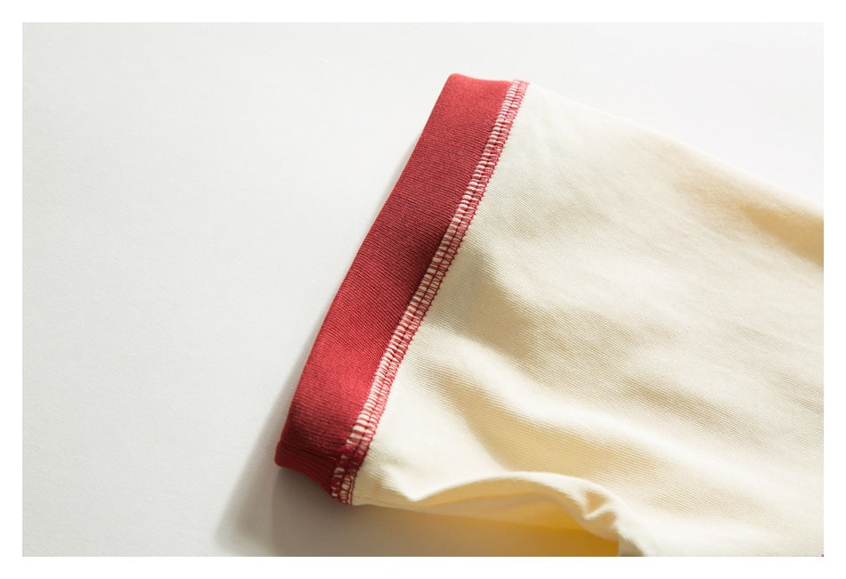 Close-up of a cream sleeve with a wide red cuff and contrasting overlock stitching.