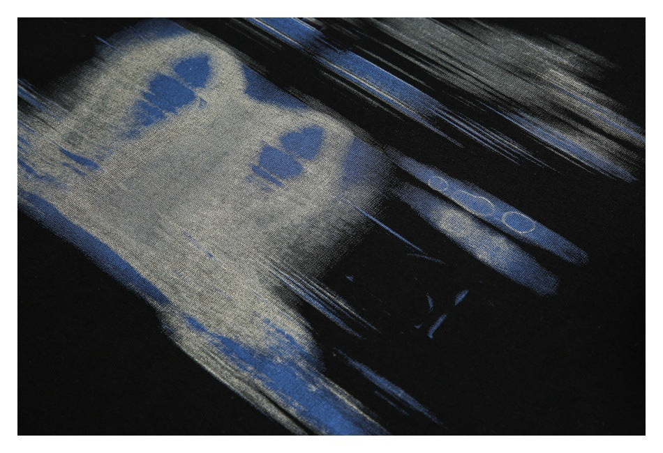 Angled close-up of the abstract blue and gray graphic on the black T-shirt.