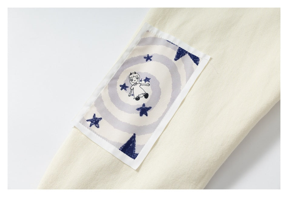 Cream jacket sleeve with a rectangular patch showing a small figure, stars, and circular stripes.