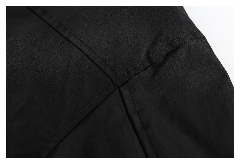 Close-up of intersecting stitched seams on black jacket fabric.