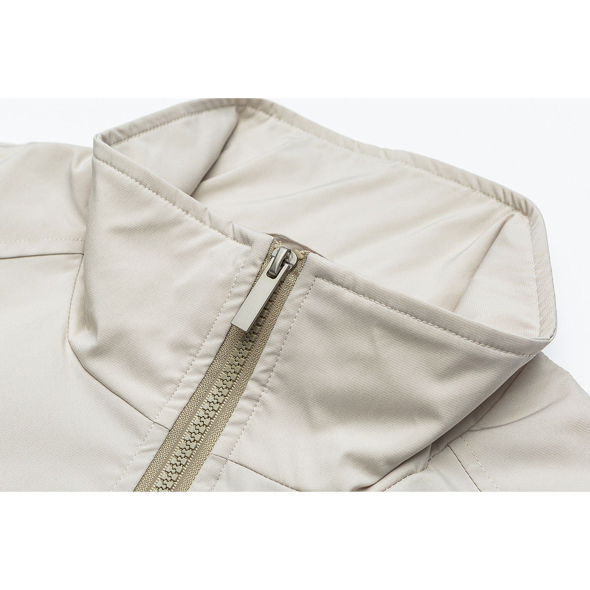 Close-up of a light beige jacket's raised collar and front zipper.