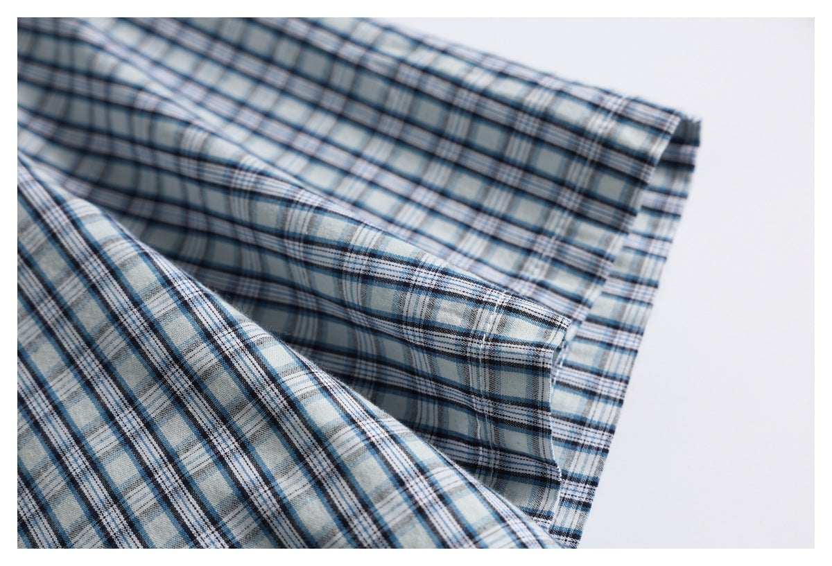 Close-up of a blue, gray, and white plaid shirt fabric folded into soft layers.