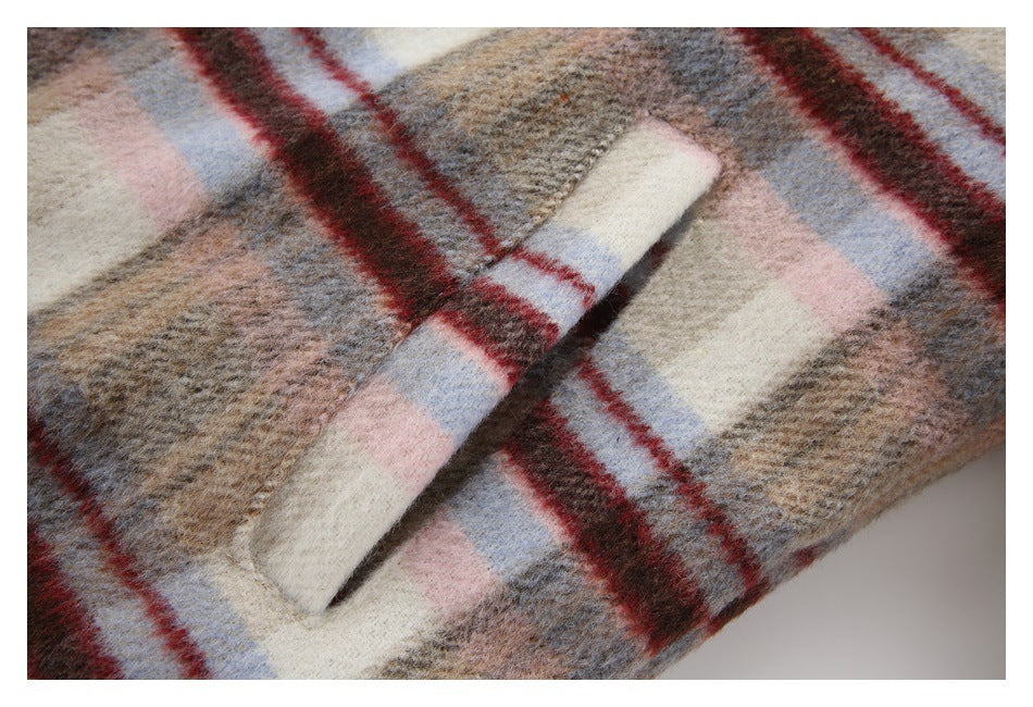 Close-up of a slanted welt pocket on a beige, pink, blue, and burgundy plaid coat.