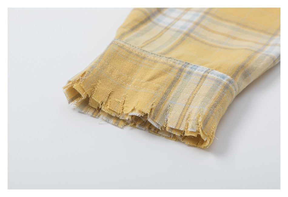 Close-up of a frayed edge on a mustard yellow, cream, and gray plaid garment.