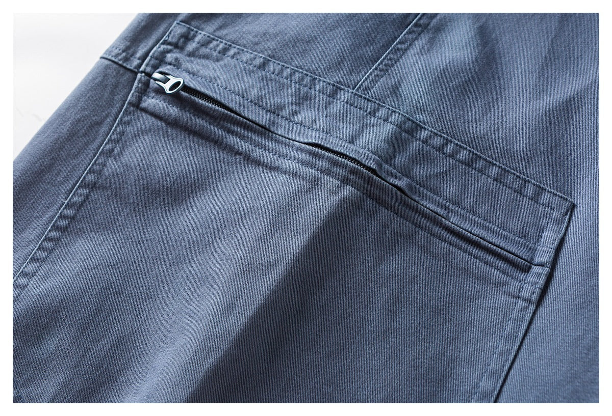 Close-up of a diagonal zip pocket with a metal pull on blue-gray pants.