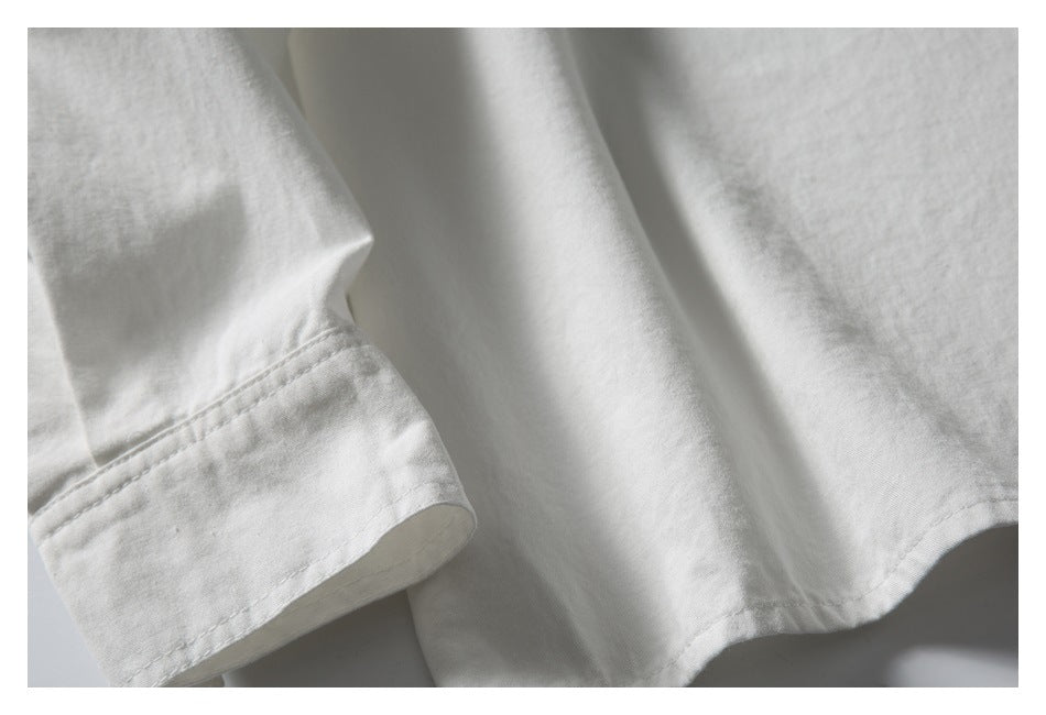 Close-up of a white shirt’s cuff and hem stitching.