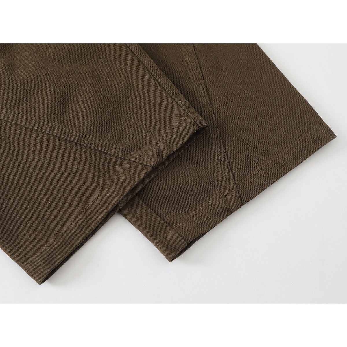 Close-up of the brown trouser leg hems and stitched seams.