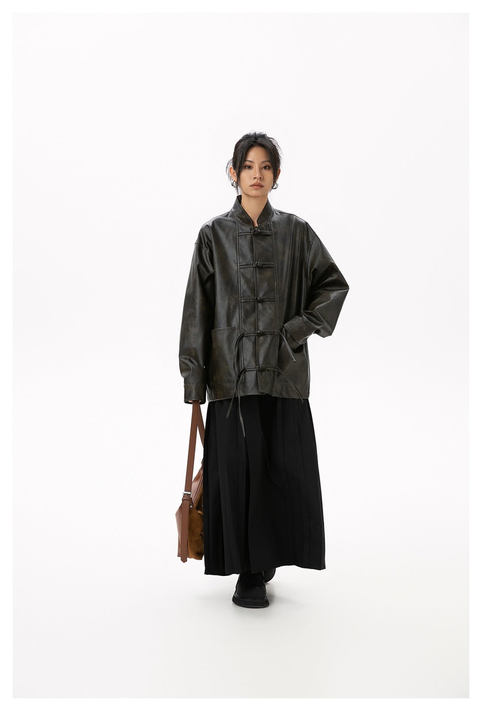 Full-length model wearing a dark brown frog-button jacket with a black skirt and carrying a brown bag.