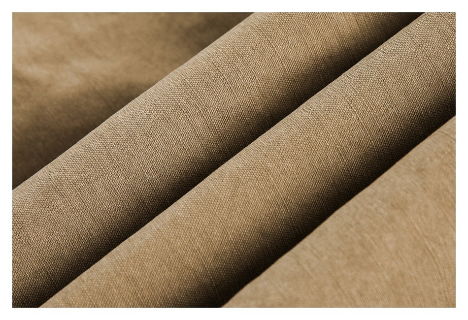 Extreme close-up of textured tan garment fabric folded into soft diagonal ridges.