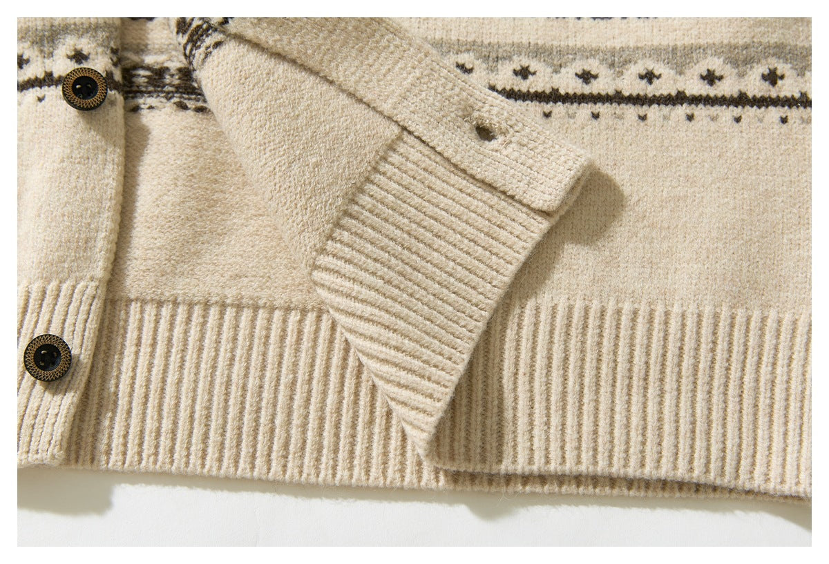 Close-up of a cream patterned knit cardigan showing dark buttons, a ribbed cuff, and ribbed hem.