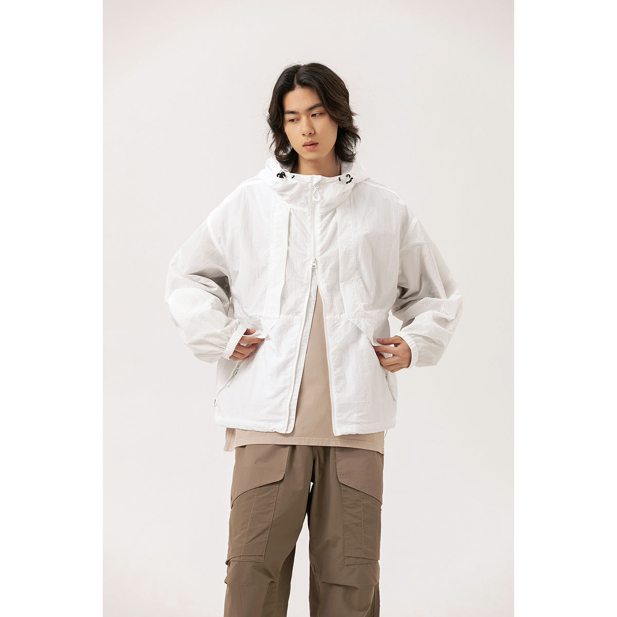 Model wearing a white hooded zip jacket with front pockets and adjustable hood toggles.