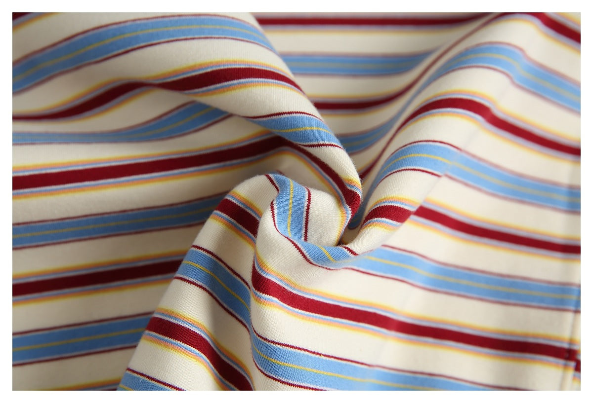 Close-up of cream fabric with wavy horizontal stripes in blue, burgundy, and yellow.