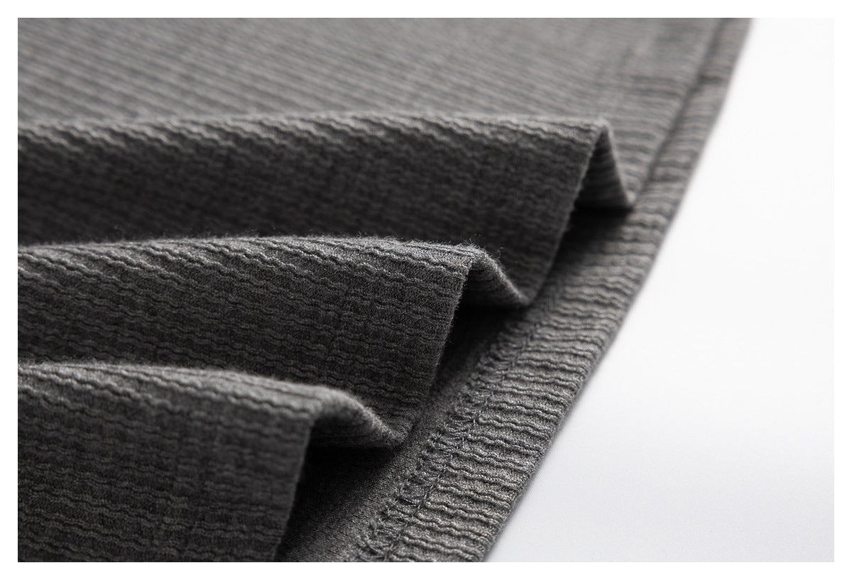 Close-up of folded gray knit fabric and a stitched garment edge.