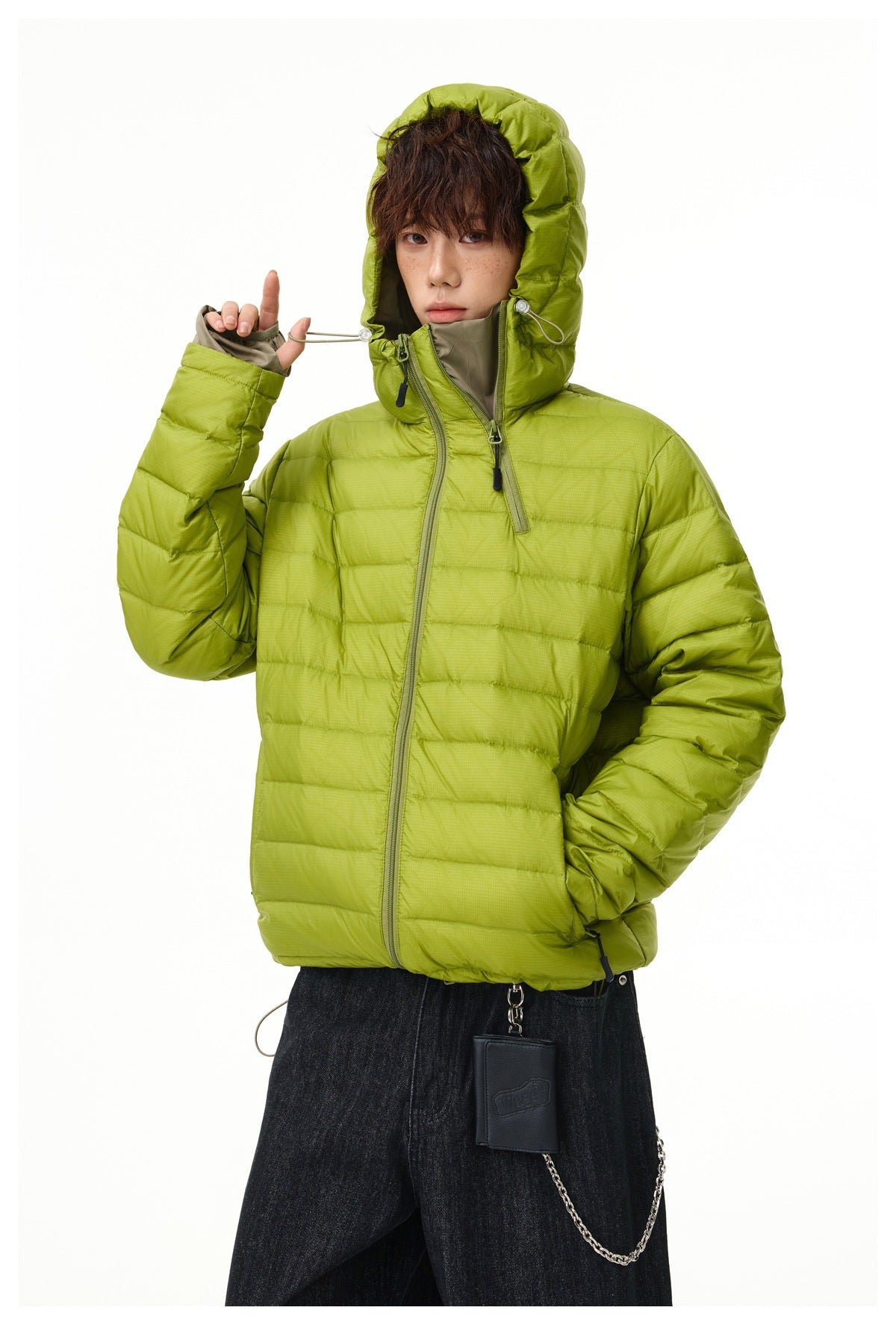 Close view of a lime-green quilted jacket, showing its oversized hood, drawcords, and high collar.