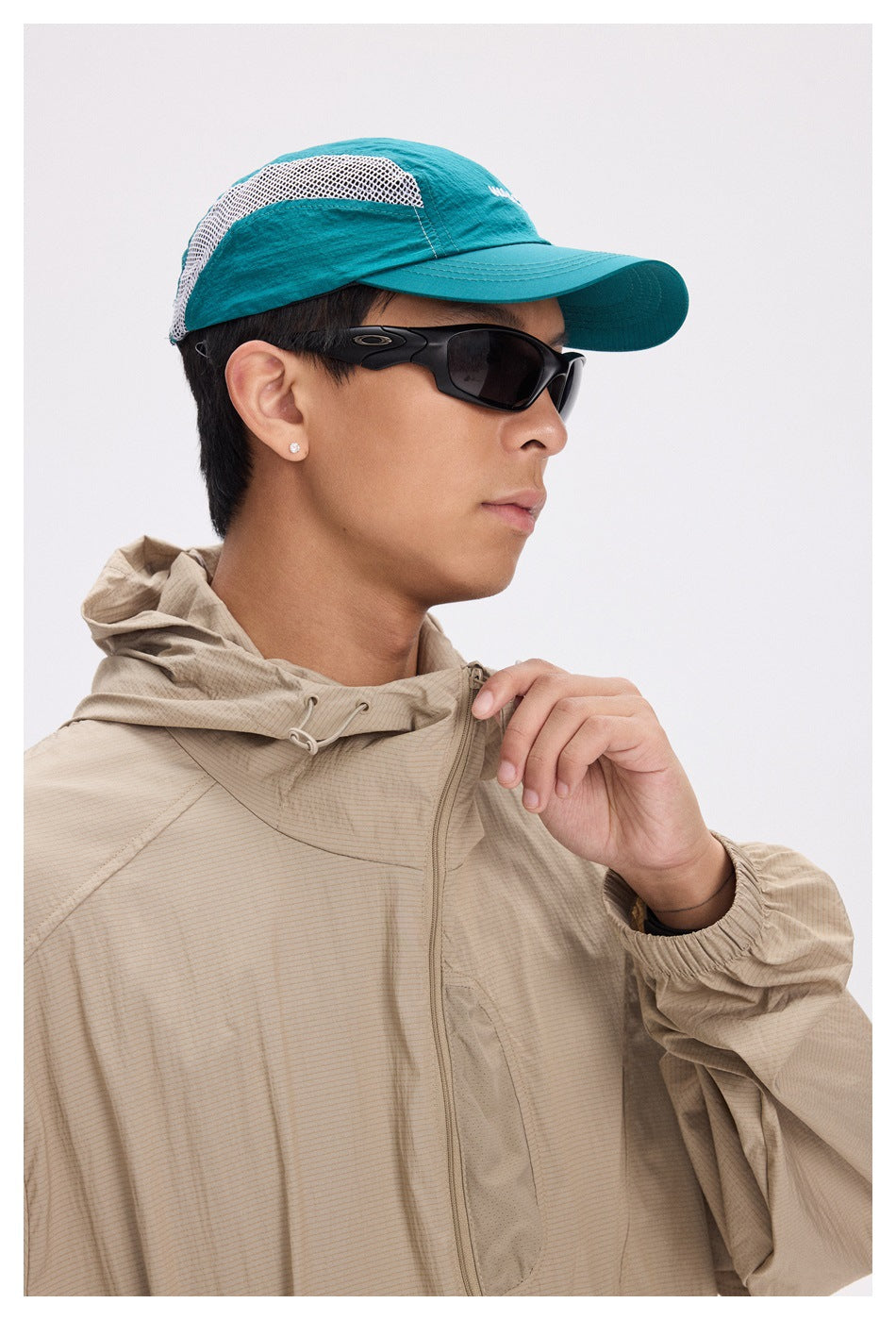 Close view of a beige hooded jacket with a front zipper and adjustable hood, worn by a model.