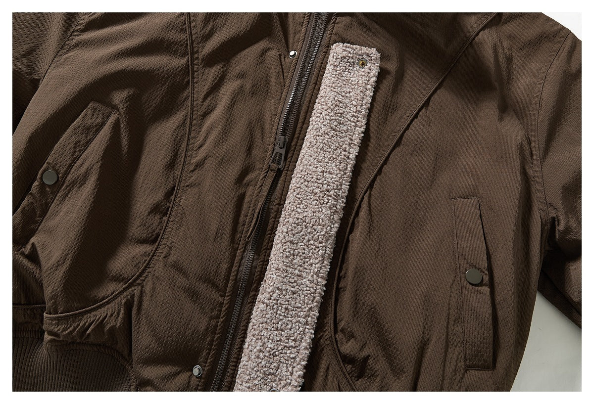 Close-up of the brown jacket's zipper, snap pockets, and a strip of light taupe textured lining.