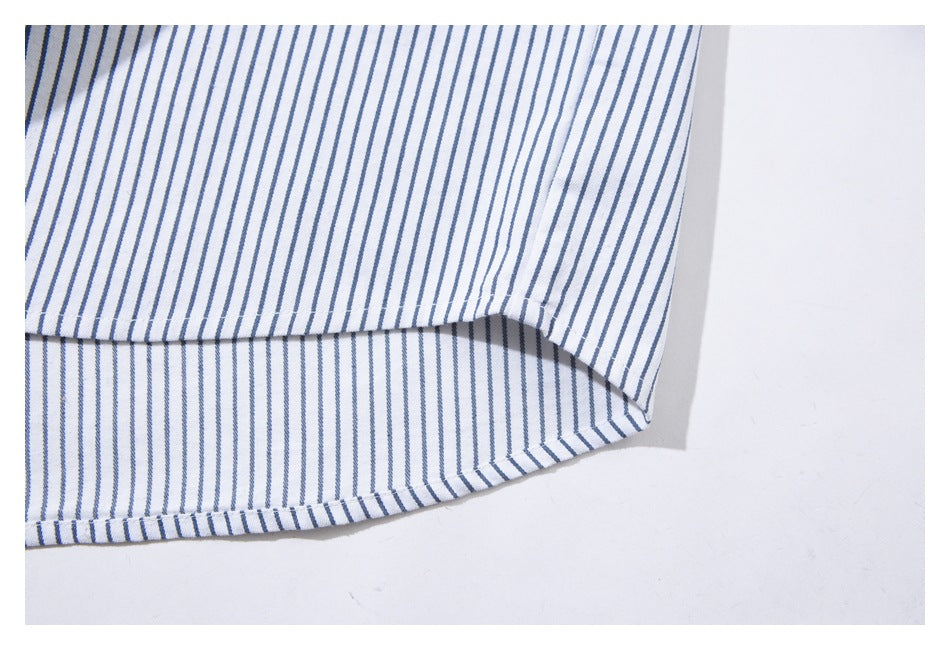 Close-up of the curved hem and stitched edge of a white shirt with narrow blue stripes.