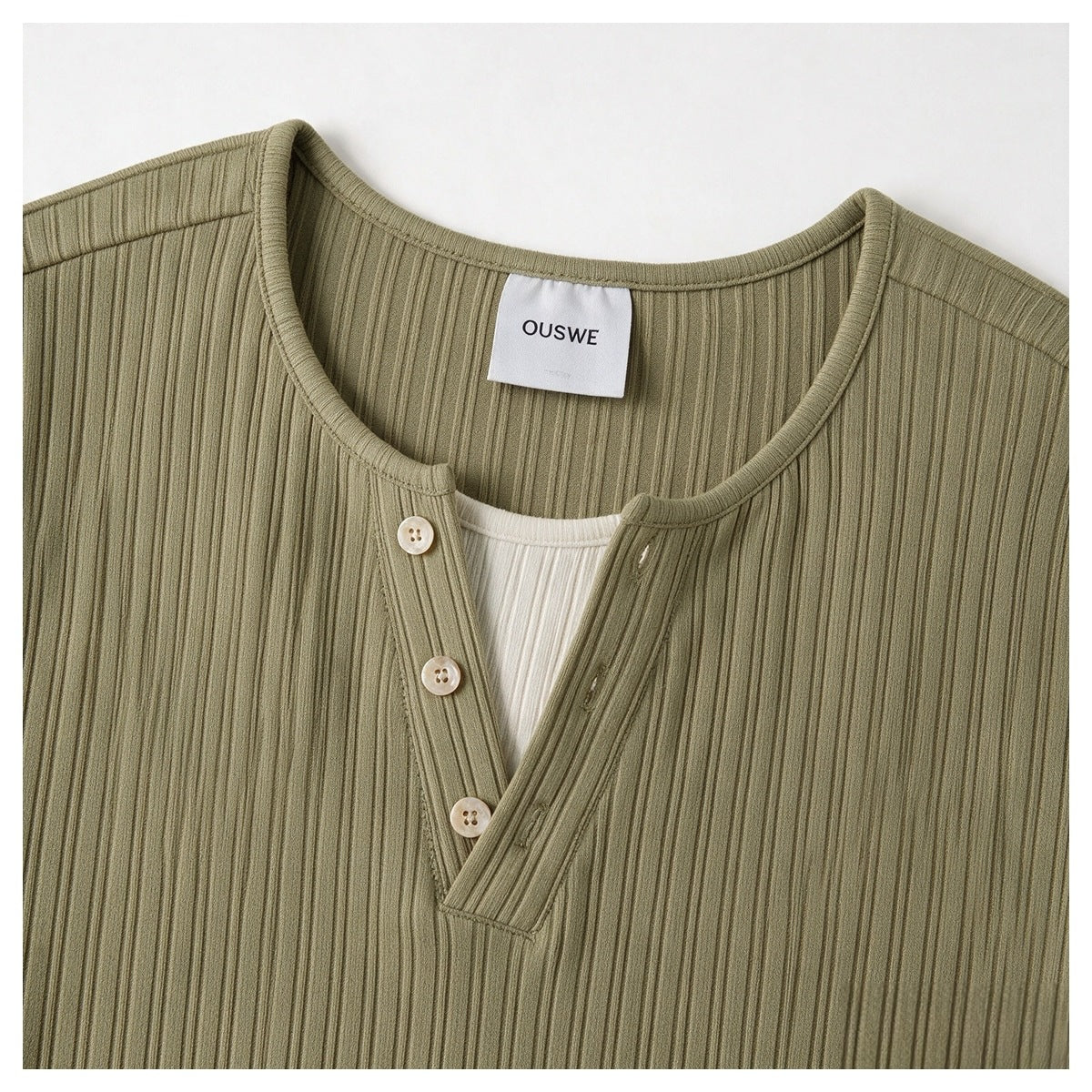 Close-up of the olive ribbed shirt's rounded neckline and three-button front placket.