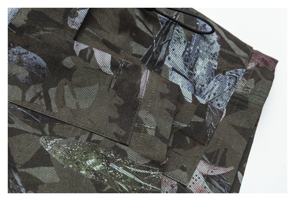 Close-up of overlapping panels and stitched seams on a dark garment with an all-over muted print.