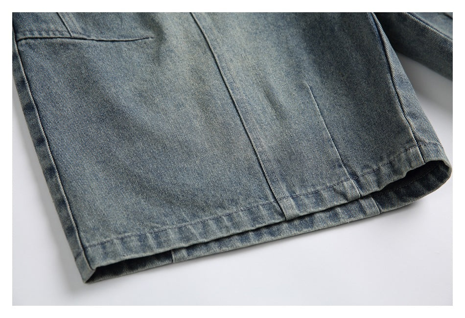 Close-up of a wide denim shorts leg showing its stitched hem and vertical panel seams.