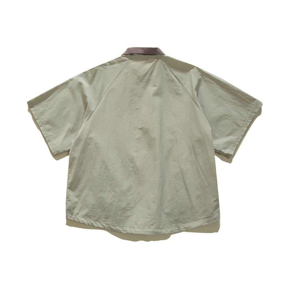 Back view of sage gray-green short-sleeve jacket with raglan sleeves and mauve collar, flat lay