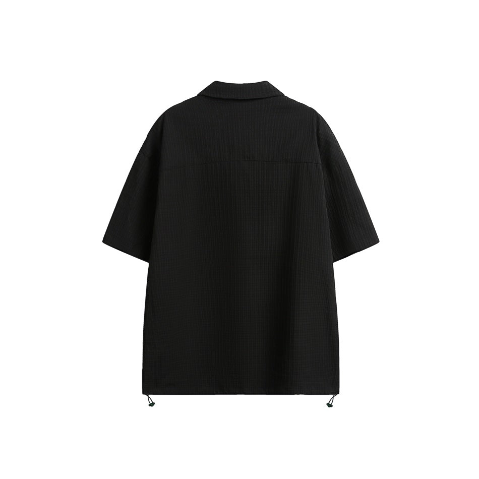 Back view of a black short-sleeve collared shirt with a straight hem and adjustable drawcords at the sides.