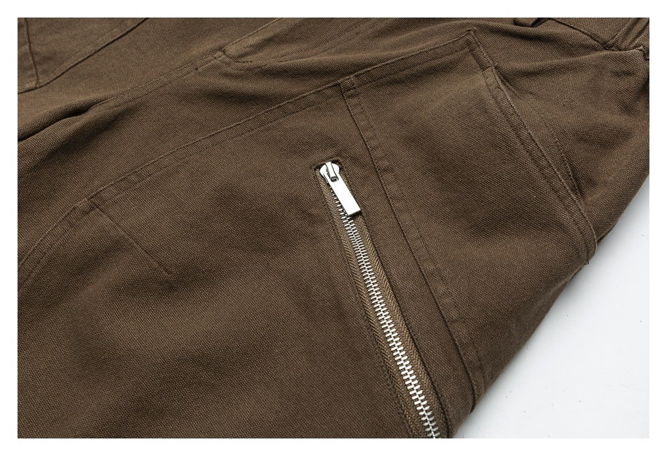 Close-up of brown trousers with a silver zipper pocket and stitched panels.