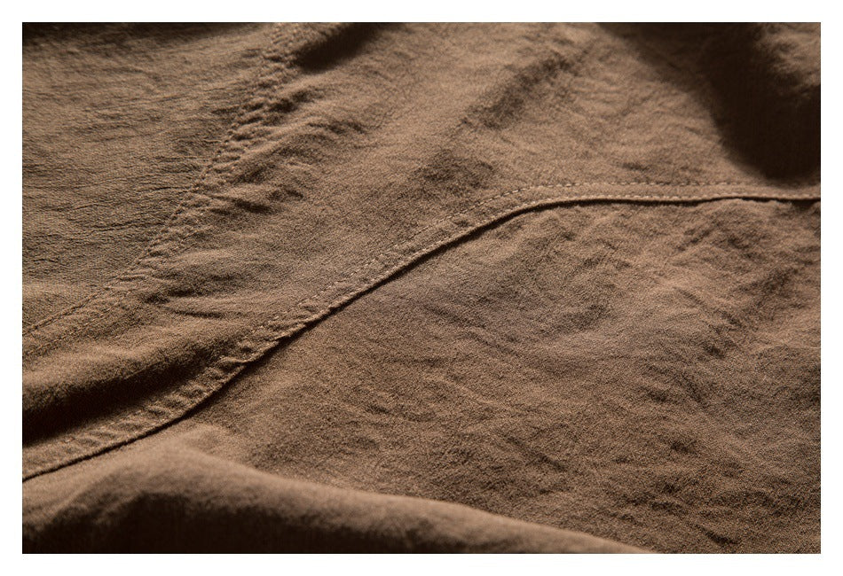 Close-up of brown garment fabric with a curved stitched seam and visible texture.