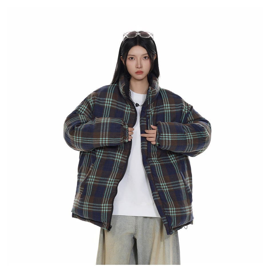 Model showing an open brown, navy and teal plaid puffer jacket over a white top.