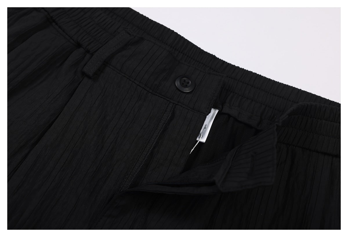 Close-up of the black trousers' buttoned waistband and partially open zip fly.