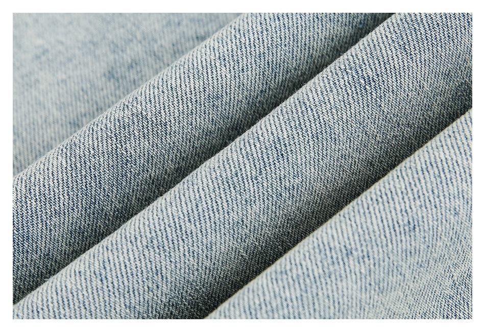 Close-up of light blue denim folded into ridges, showing its woven texture.
