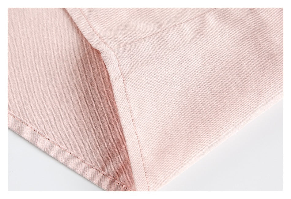 Close-up of a pale pink shirt seam and folded edge with visible stitching.