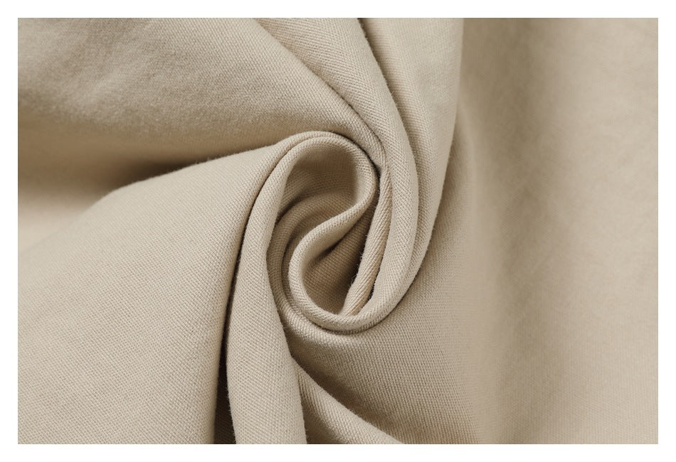 Close-up of beige fabric gathered into a soft fold, showing its fine surface texture.