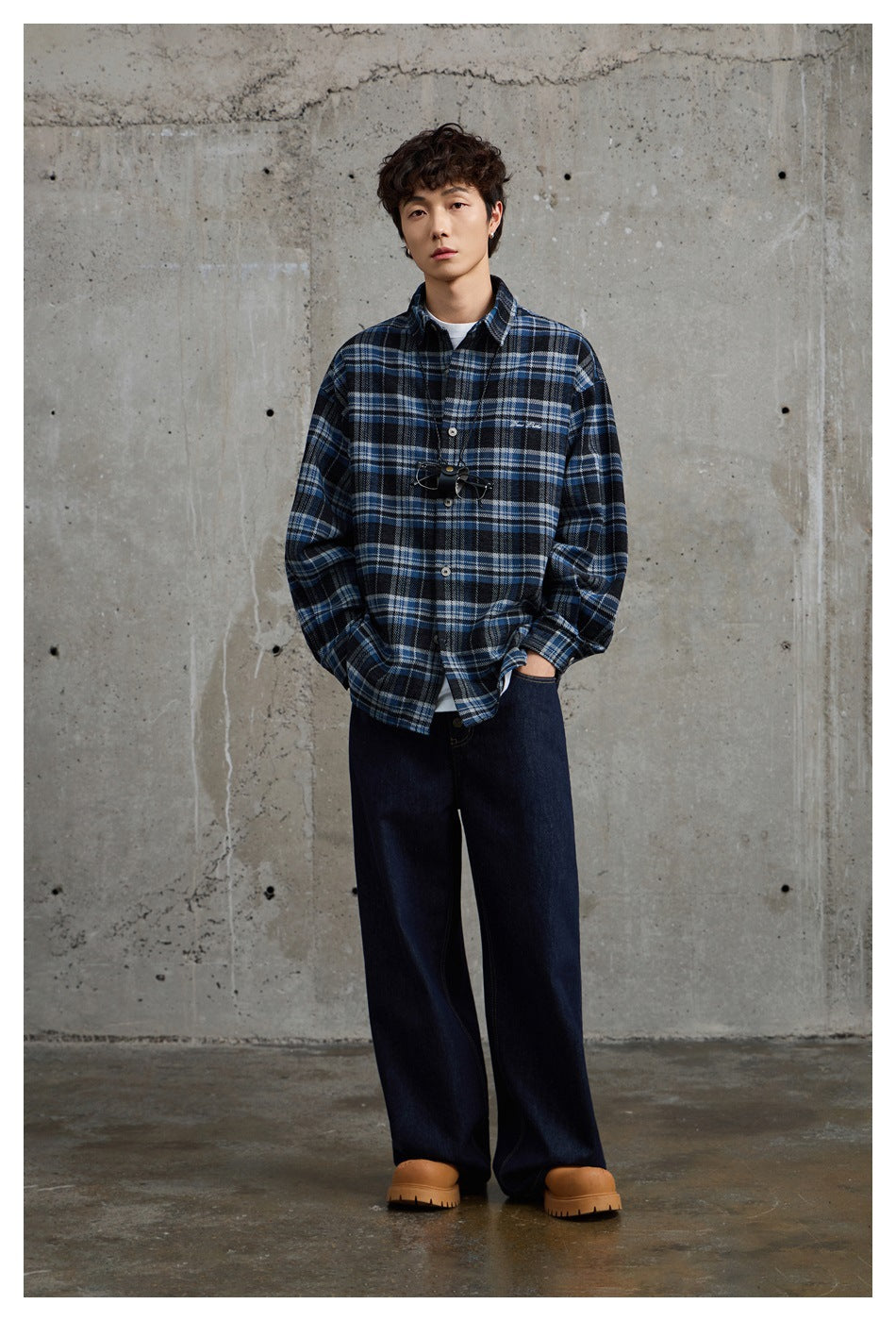 Full-length model wearing a blue-and-black plaid button-up shirt with dark wide-leg jeans.