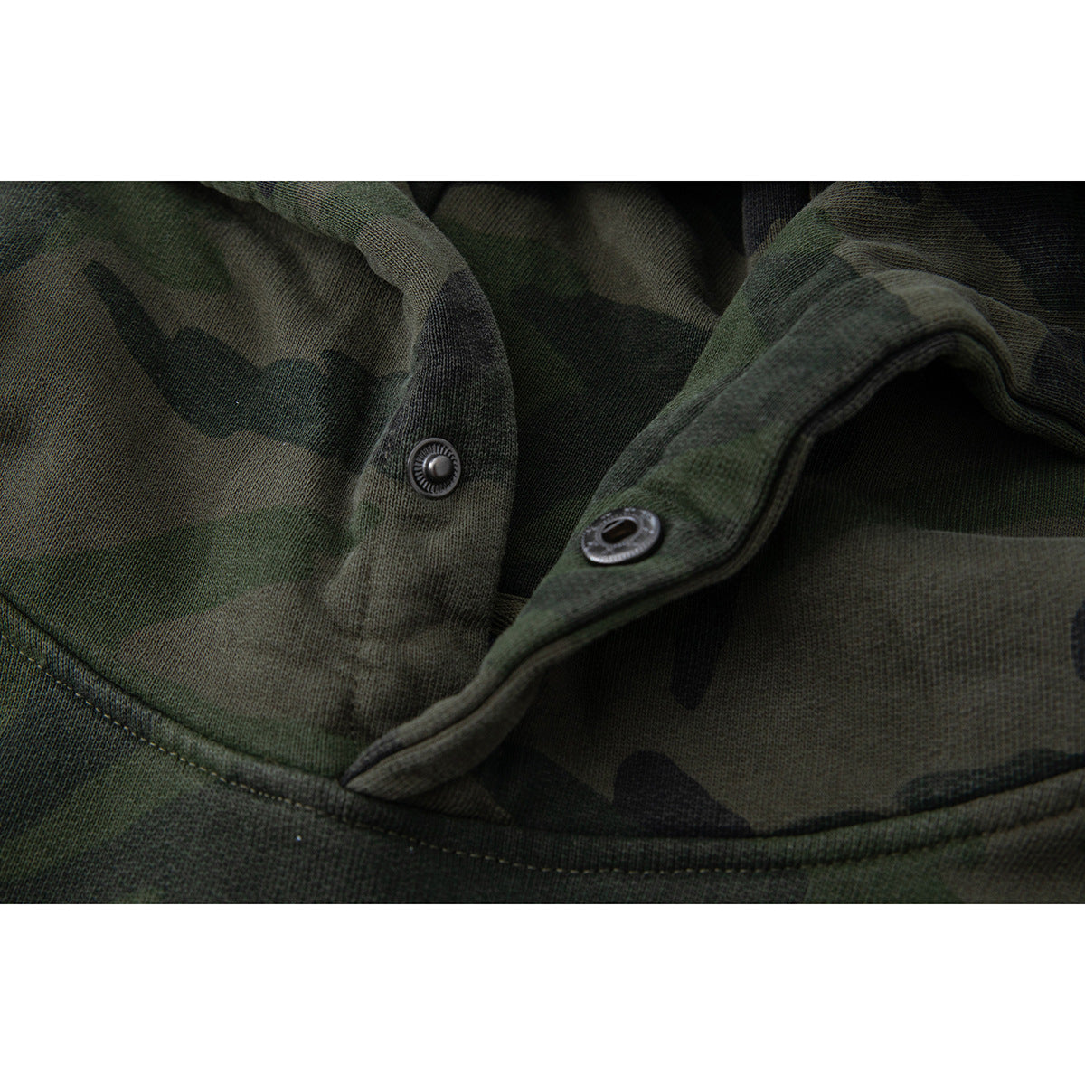 Close-up of the camouflage hoodie’s neckline, showing a snap fastener and its matching eyelet.