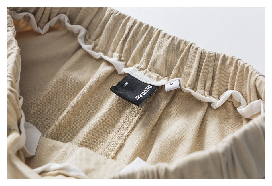 Inside view of beige trousers showing the elastic waistband, white trim, and sewn-in label.