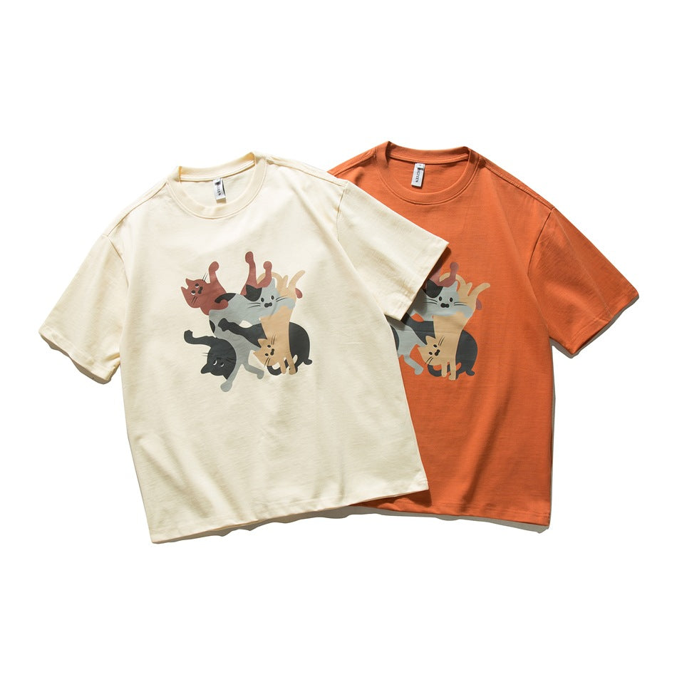 Two crew-neck short-sleeve T-shirts in cream and orange, each printed with a group of cats.