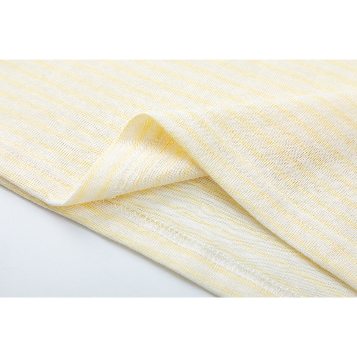 Close-up of the cream and pale yellow striped shirt's folded hem and stitching.