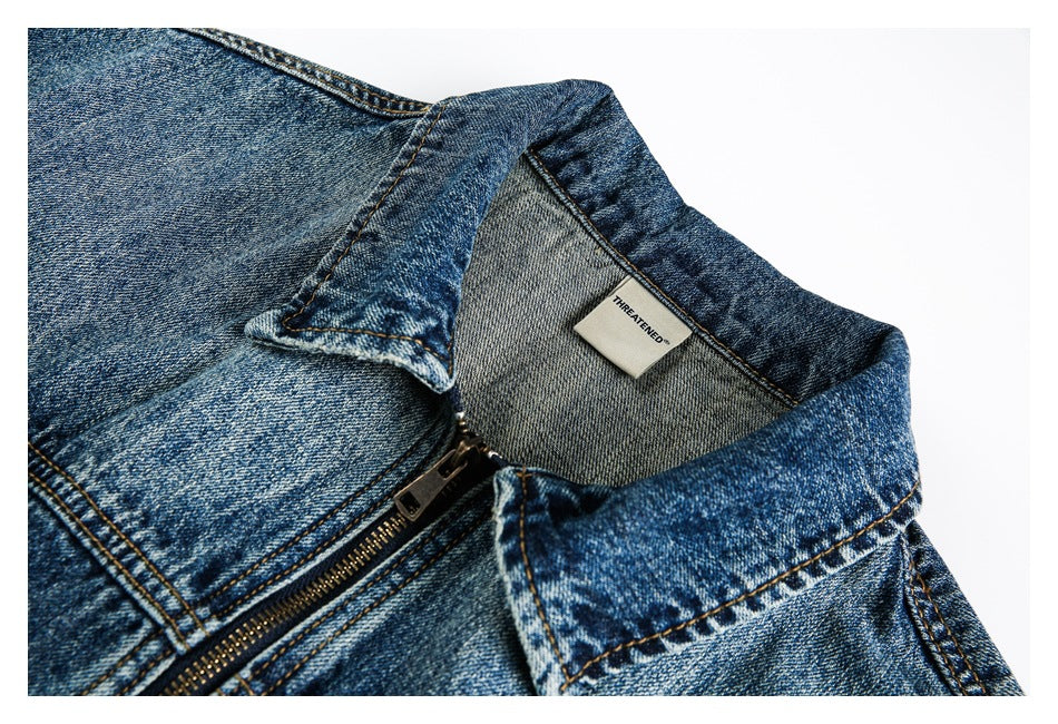 Close-up of a blue denim jacket collar, zipper, and inner neck label.