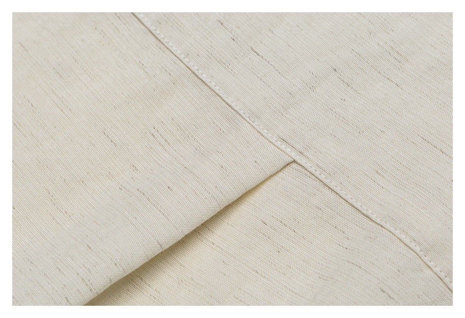 Close-up of the off-white shirt's lightly textured fabric and intersecting stitched seams.