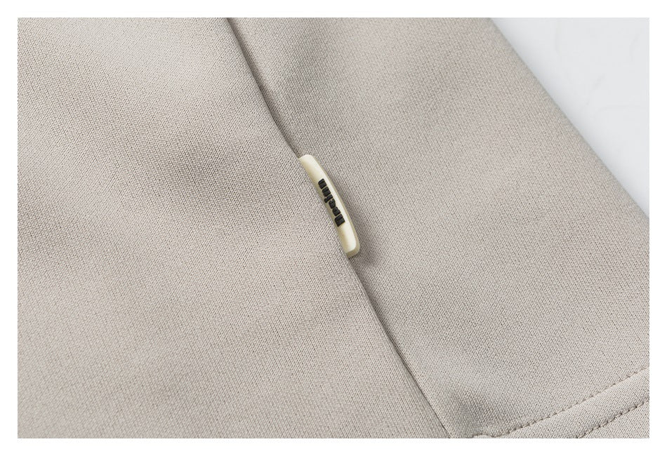Close-up of light beige garment fabric with a small cream tab bearing dark lettering.