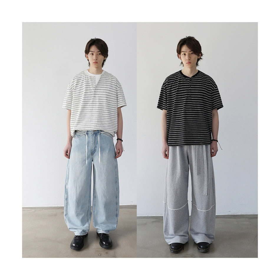 Two views of a model wearing the striped Henley T-shirt in white and in black with wide-leg pants