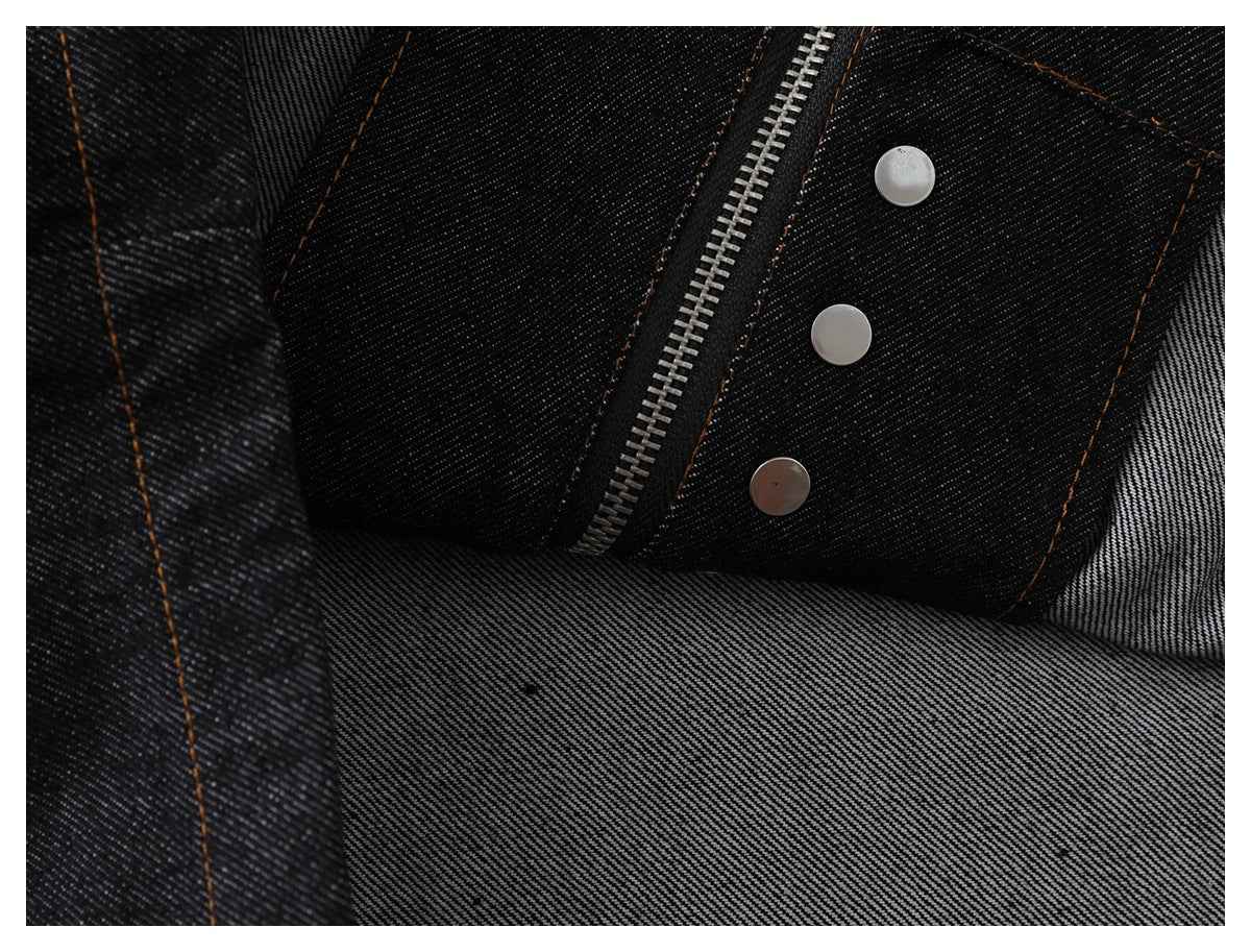 Inside view of dark denim garment construction with zipper, snaps, seams, and lighter reverse fabric.