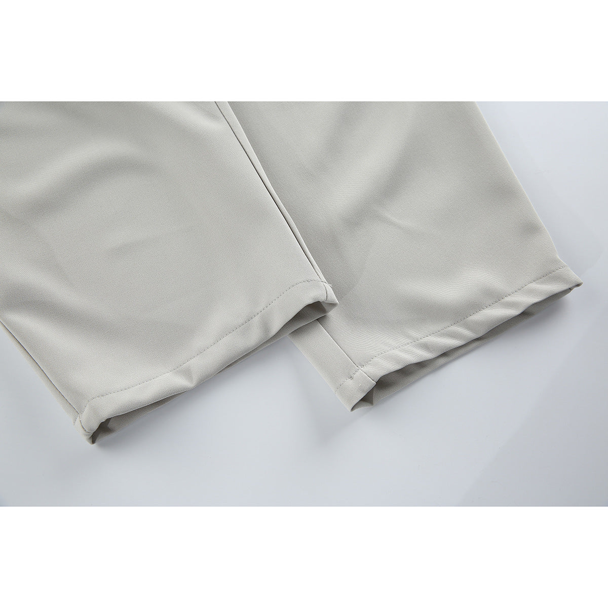 Close-up of the light gray trousers’ straight-leg hems and stitched seams.