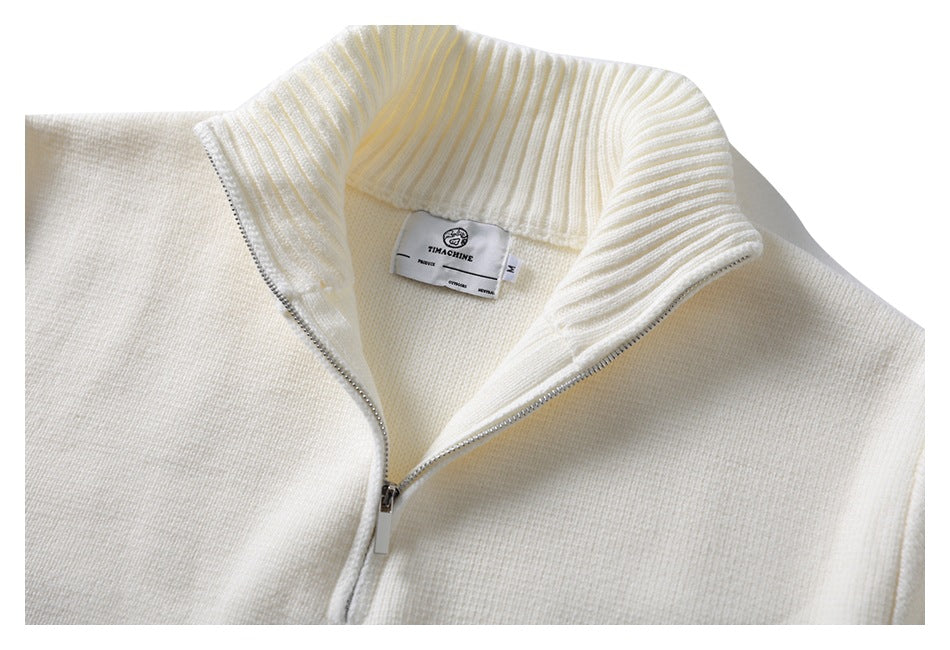 Close-up of an ivory quarter-zip sweater’s ribbed collar, silver zipper, and neck label.