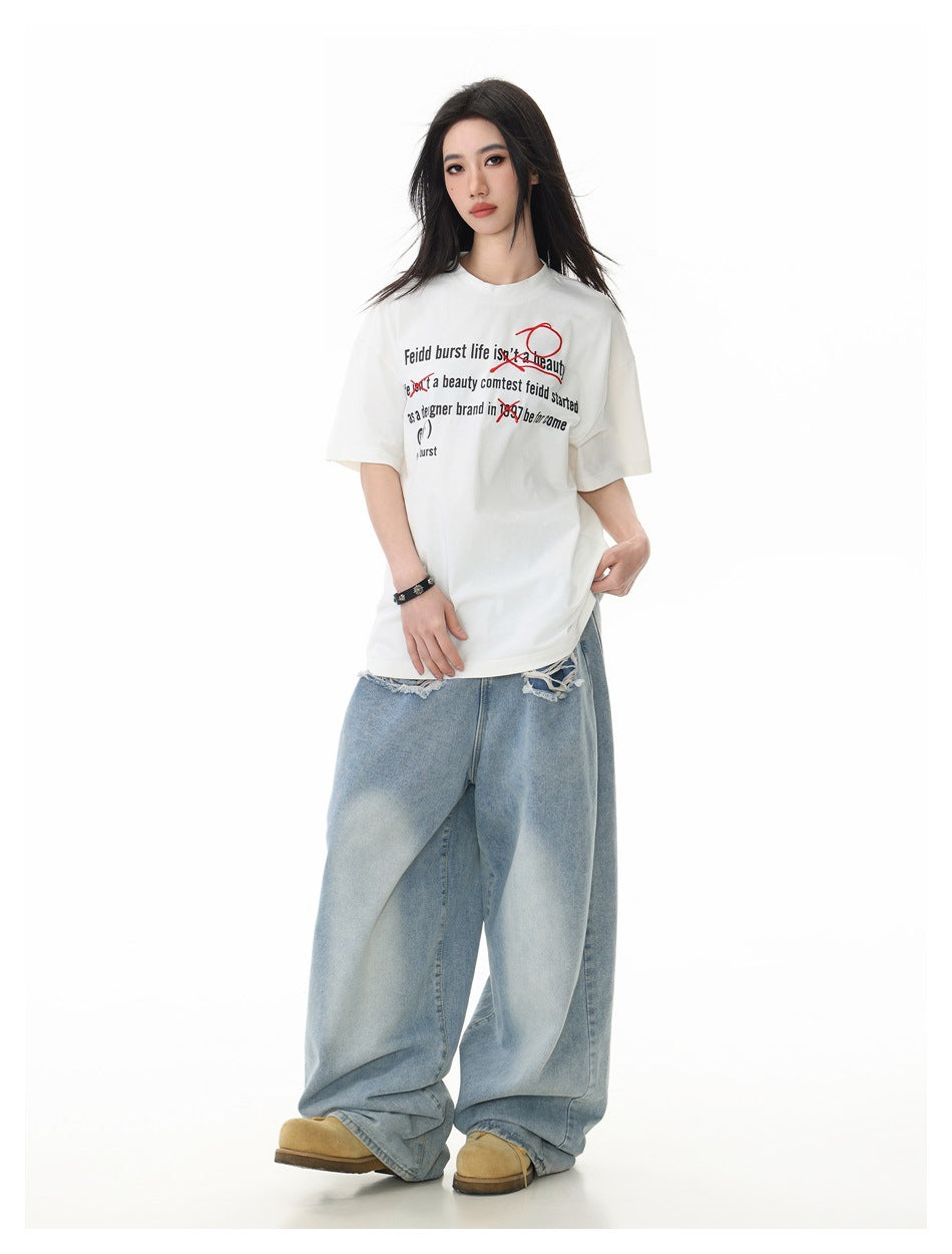 Full-length model wearing an off-white oversized graphic T-shirt, very wide light-wash jeans, and tan shoes.